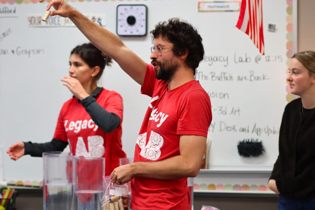 Lamp Rynearson Legacy LAB team members Cassie Wolf, Rob Vanderveen, and Elli Klein in front of a classroom