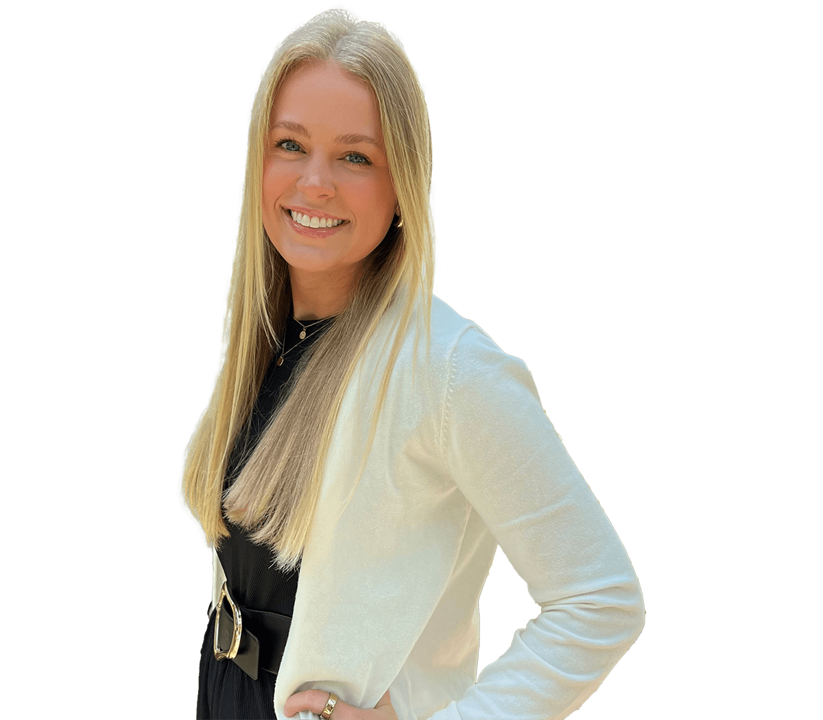 Smiling woman with long blonde hair wearing a white blazer over a black dress, posing with hands on hips.